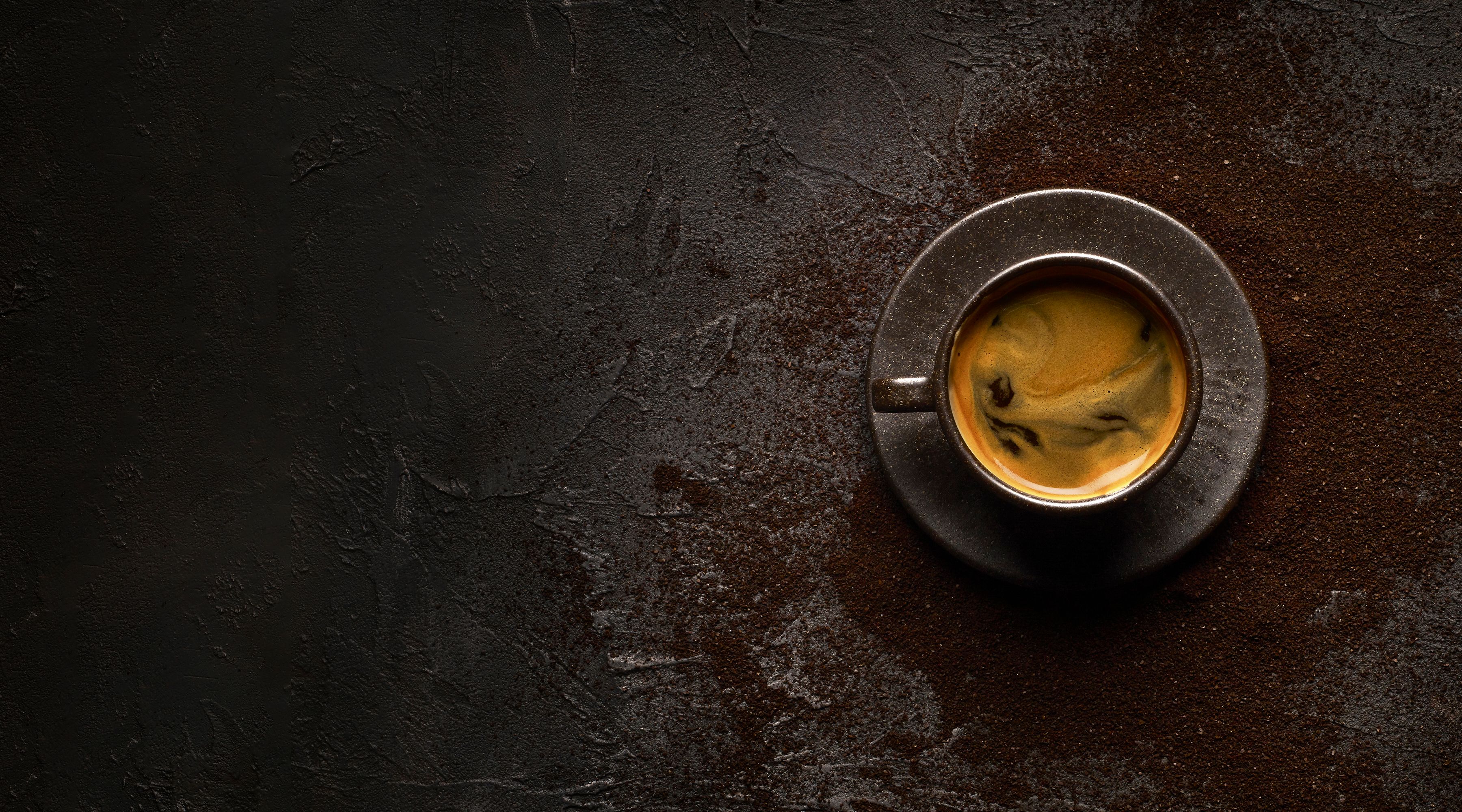 overhead shot of cup of coffee with crema and grounds in the background 